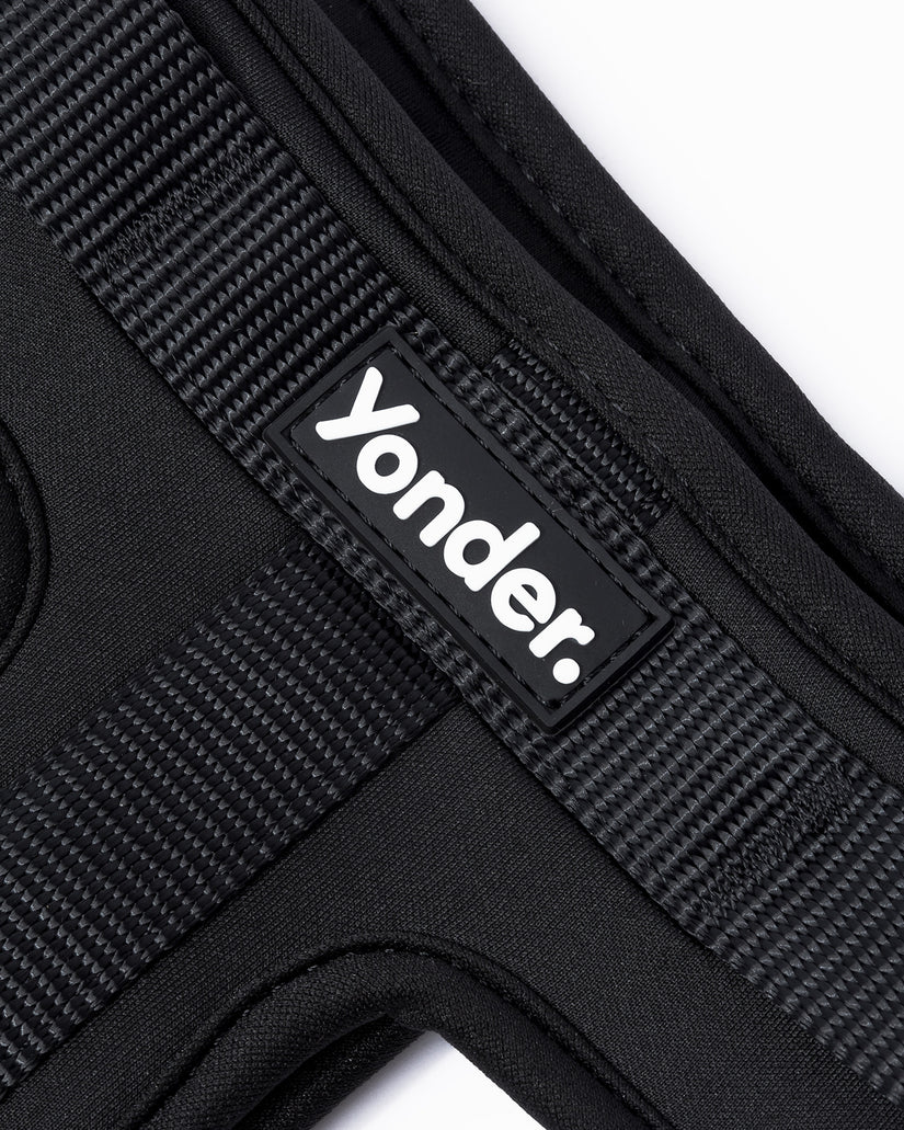 close-up of a black dog harness with 'yonder.' branding on a white background